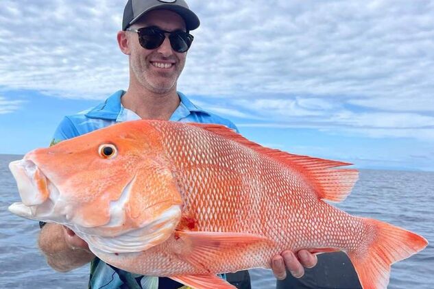 Angler holding up a freshly caught Red emperor