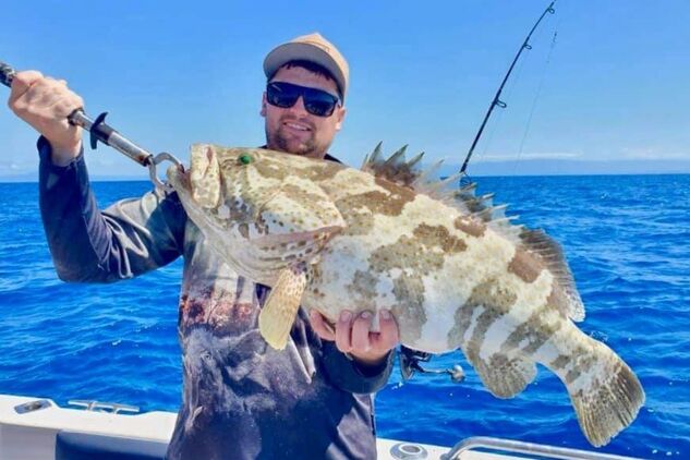 Angler holding up a freshly caught Potato grouper