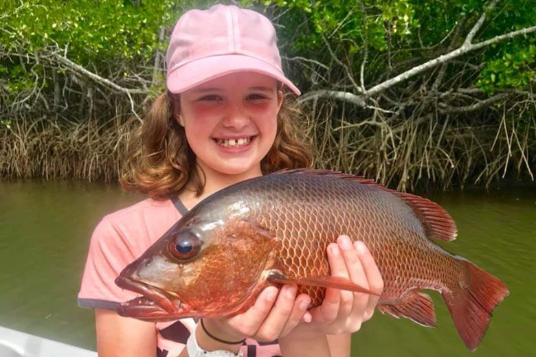 Girl holding up a Mangrove Jack fish